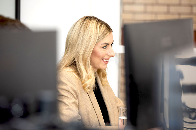 Woman smiling at computer screen.