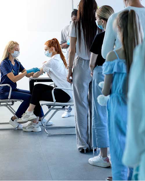Nurse giving injection to a queue of people